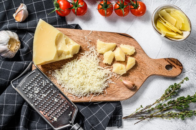 grated parmigiano reggiano cheese and metal grater on wooden cutting board gray background top view 89816 8677