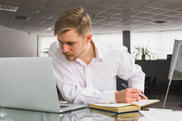 businessman looking laptop while writing schedule diary 23 2147838570